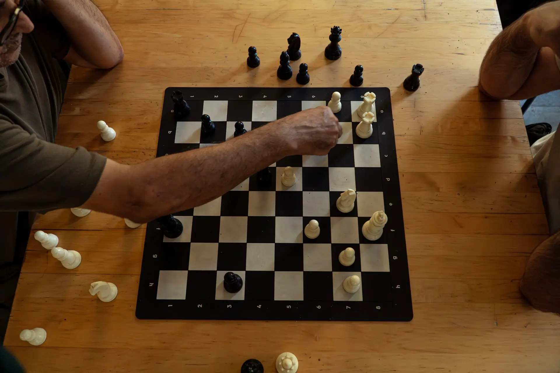 Two players reaching across a chess board
